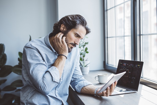 Businessman working using multiple devices at an office near a window.