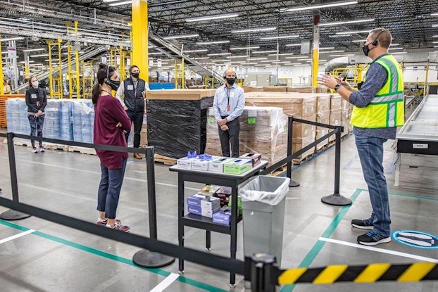 Amazon employee speaking to people inside the warehouse.