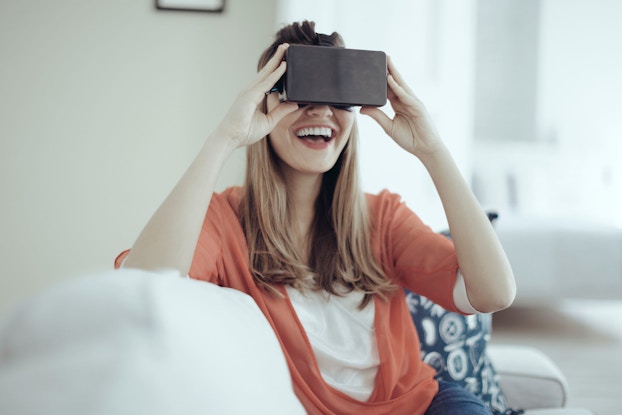 A young woman uses head-mounted virtual reality goggles.