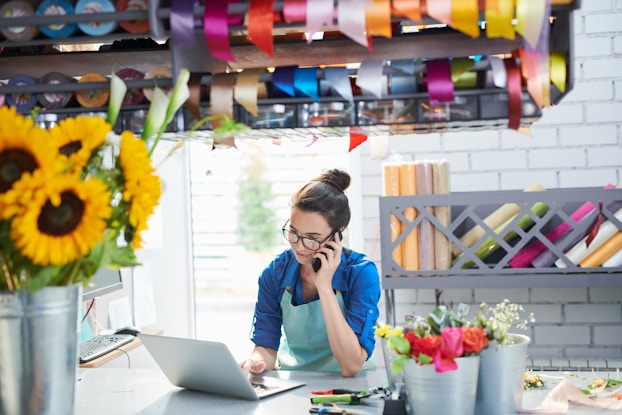 Business woman on phone and laptop inside of her shop.