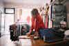 A businesswoman owner of a clothing retail store leans against the sales counter. She is talking on the phone and taking notes on a pad of paper.