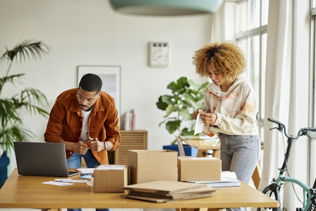 Two people working on packaging up items in an office.