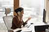 Confident woman in her home office looking at a computer screen and talking on the phone.