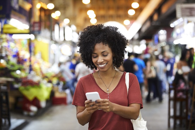 Smiling woman looking at her phone inside a supermarket.