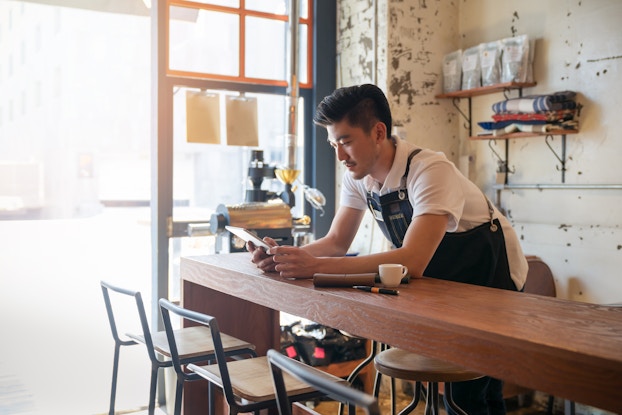 Person working inside a cafe on a tablet.