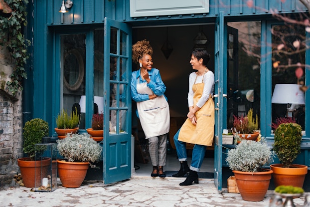Two business owners standing outside their shop laughing.