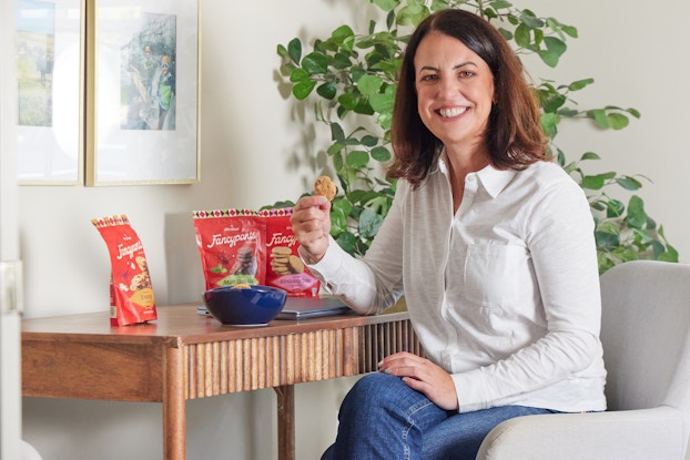 Maura Duggan, Co-Founder and CEO of Fancypants Baking Co., sitting at a desk with bags of her cookies.
