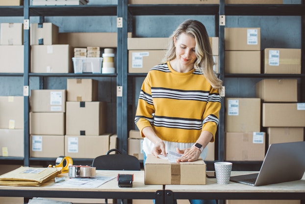 Woman boxing and stacking packages for shipment.