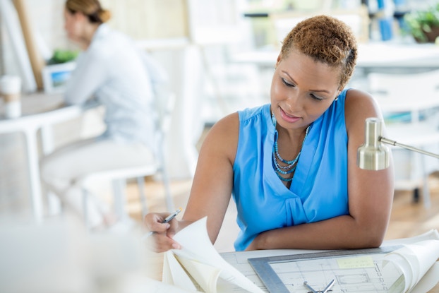 Woman looking over paperwork at a desk.