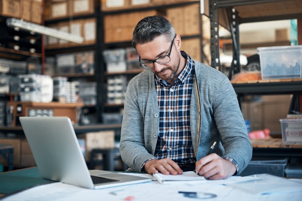 Man sitting inside his business doing paperwork at a desk.