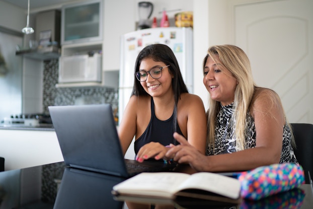 Two people working on project on laptop in a home