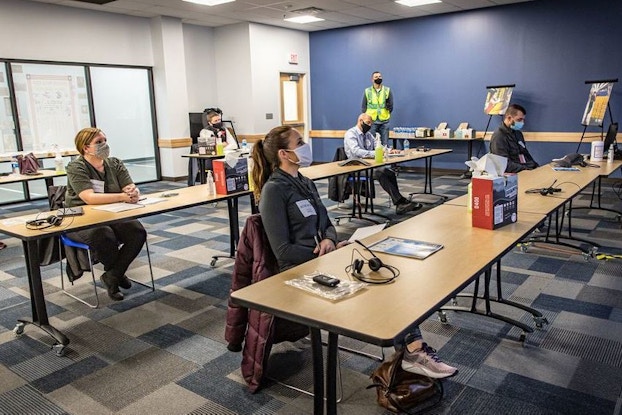People attending Amazon warehouse tour and sitting at desks for a presentation.