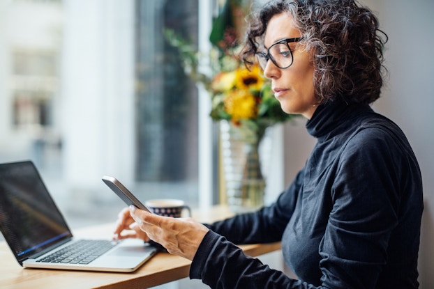 Person on both her laptop and phone.