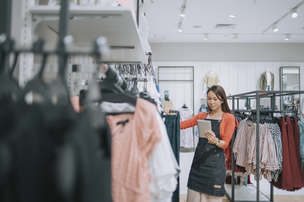 Woman working in clothing store using a tablet to count inventory.