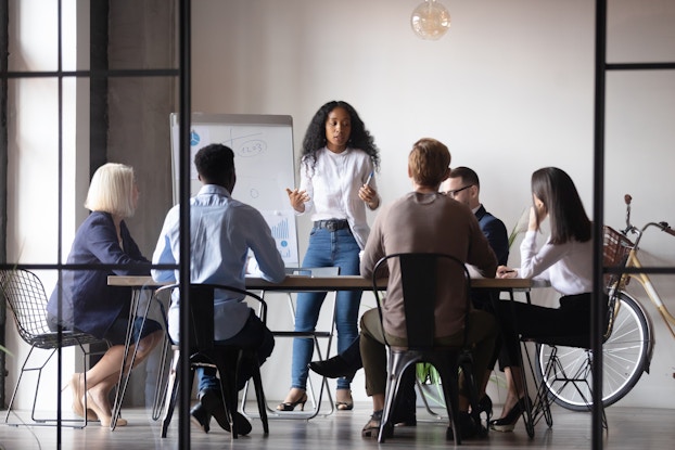 woman presenting to a team of people in a conference room