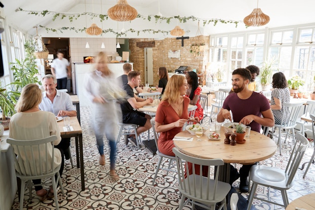 Lunchtime customers are pictured eating in a brightly lit, busy cafe.