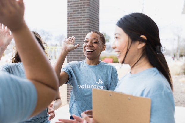 Group of happy volunteers high-fiving each other.