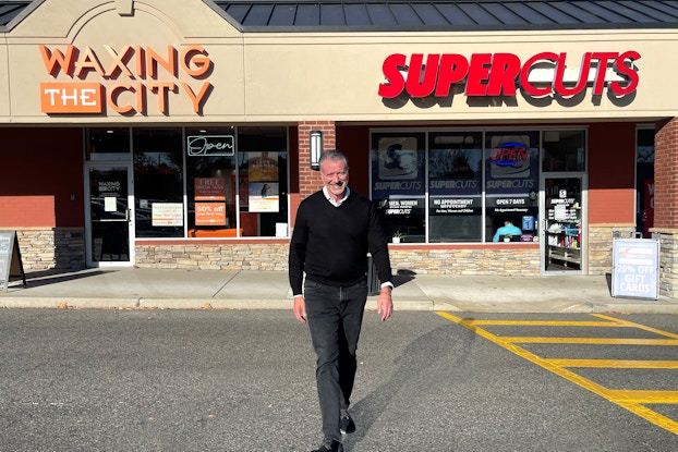 Gary Robins, franchise owner of 63 Supercuts stores stands outside one of his franchises.