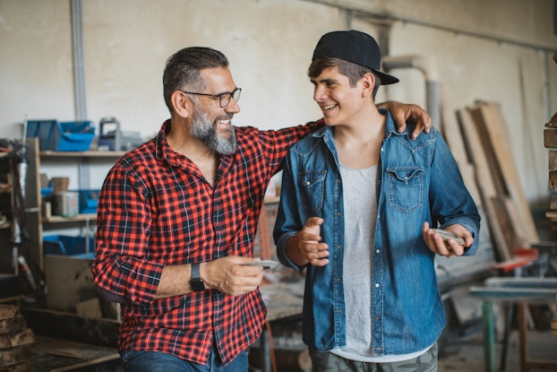 Teenager with an adult talking in a construction workplace.