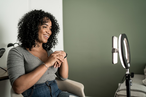 Woman sitting down and recording a video using her phone.
